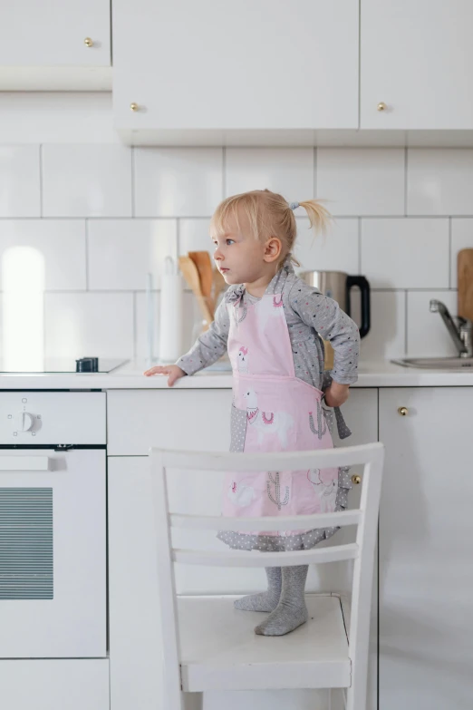 the little girl is standing up against the counter