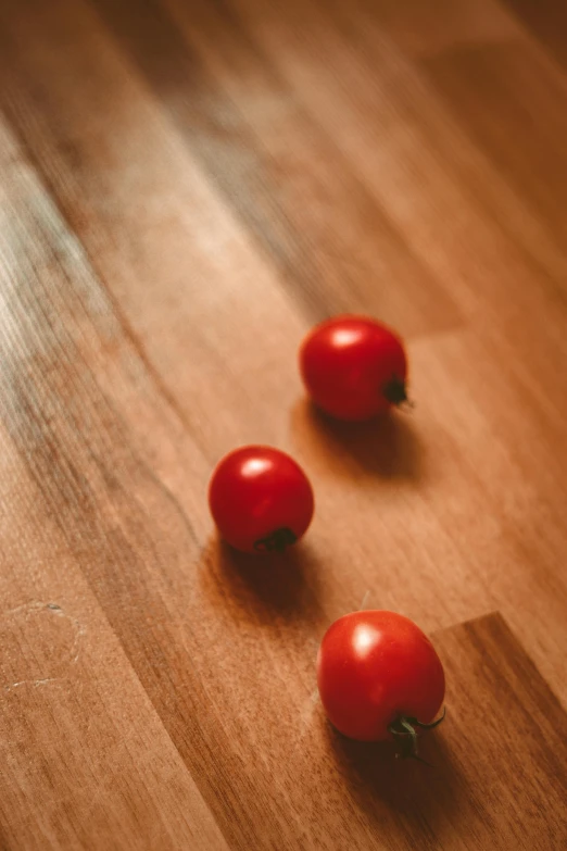 two tomatoes sitting on the wooden floor next to each other