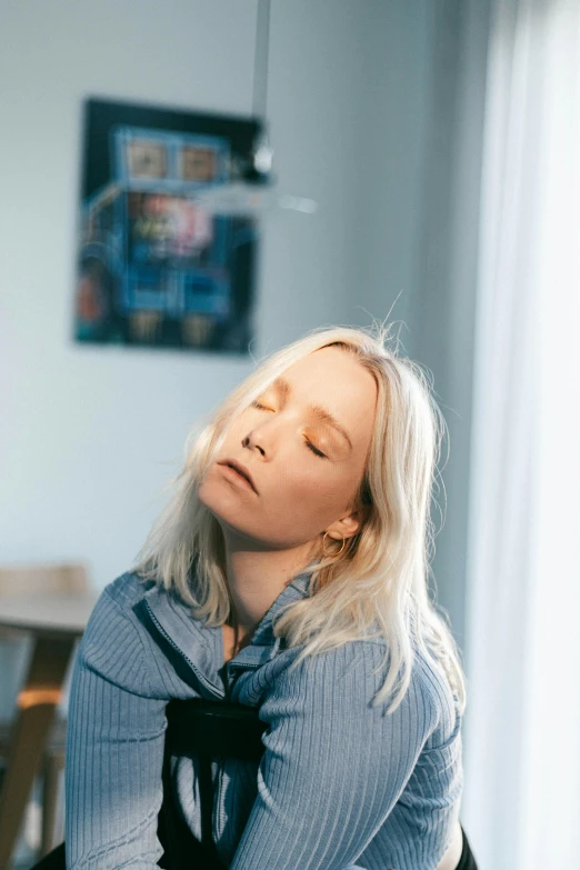 a lady that has her face tilted down, sitting in a chair