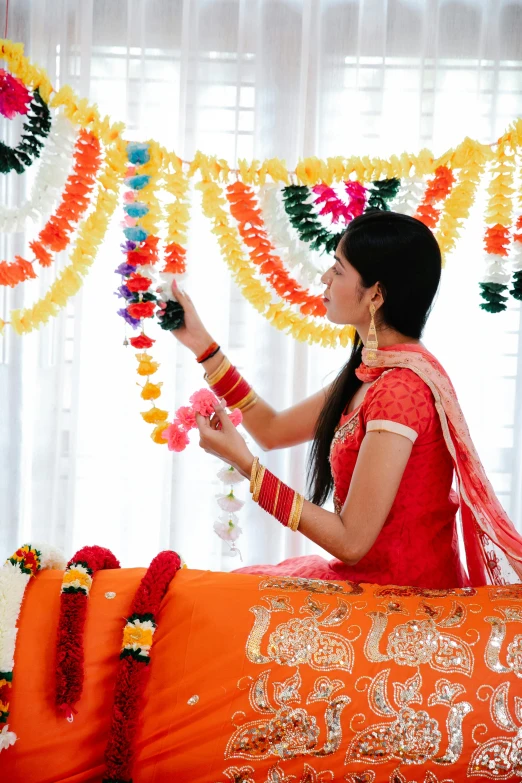 a woman in an orange saree is holding a decorative item