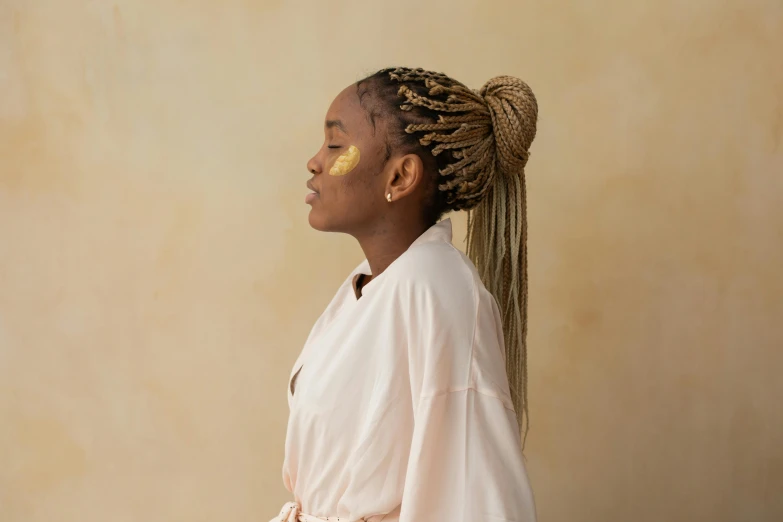 a woman with long hair standing against a tan wall