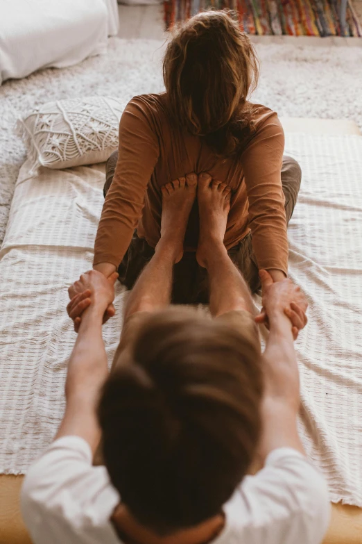 man and woman are sitting on a bed, facing the same direction