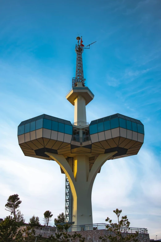 a giant tower with a blue top sits on a hillside