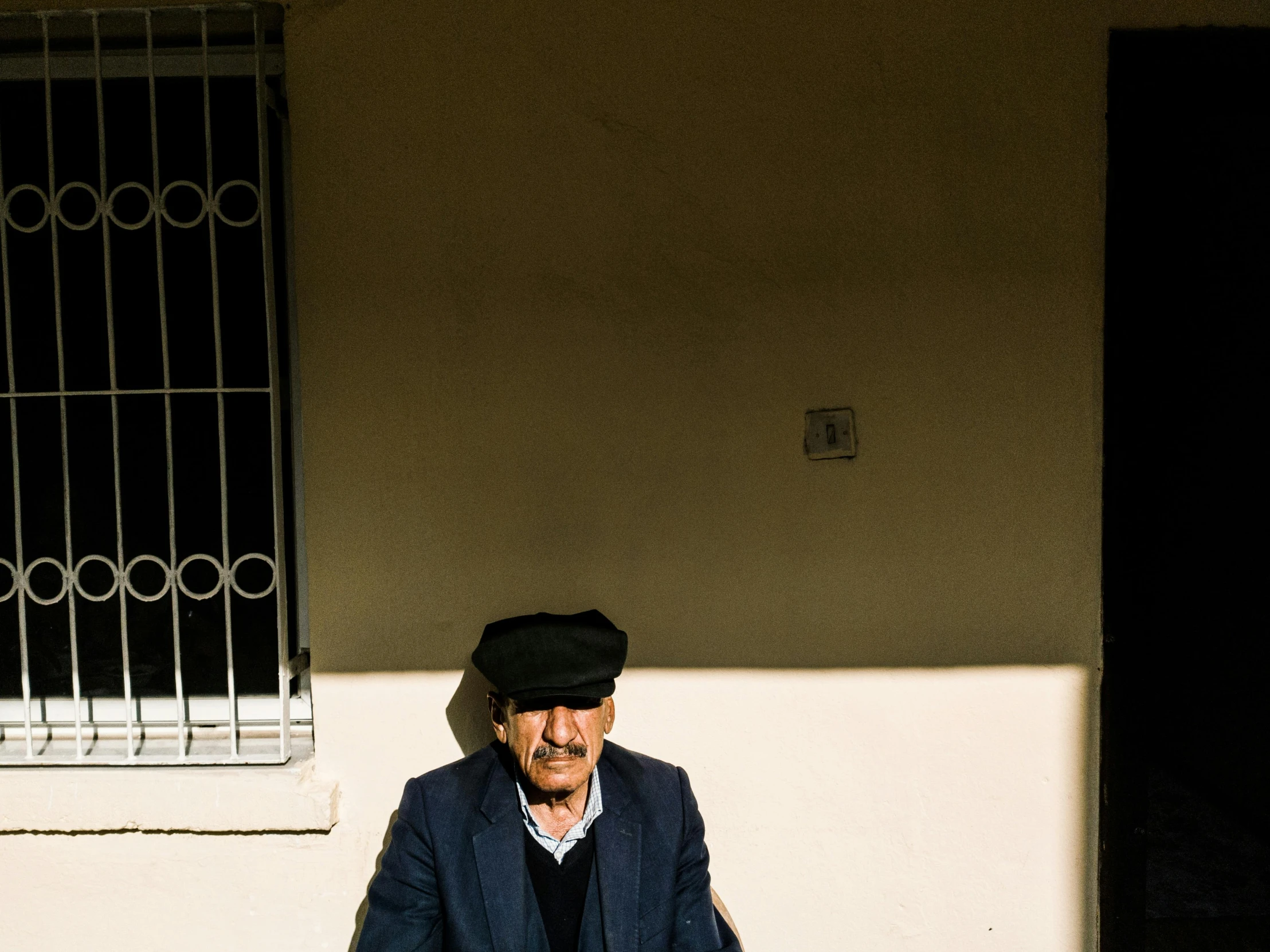 a man with a hat on standing in front of a wall