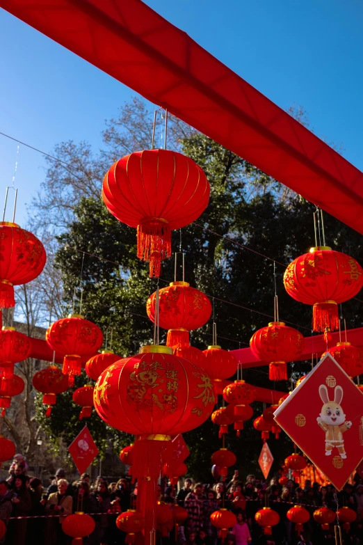 bright red lantern decoration hanging from poles with a person standing next to it