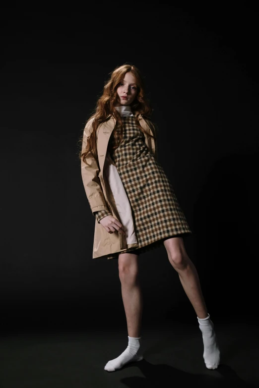 a woman poses in a trench coat with socks on