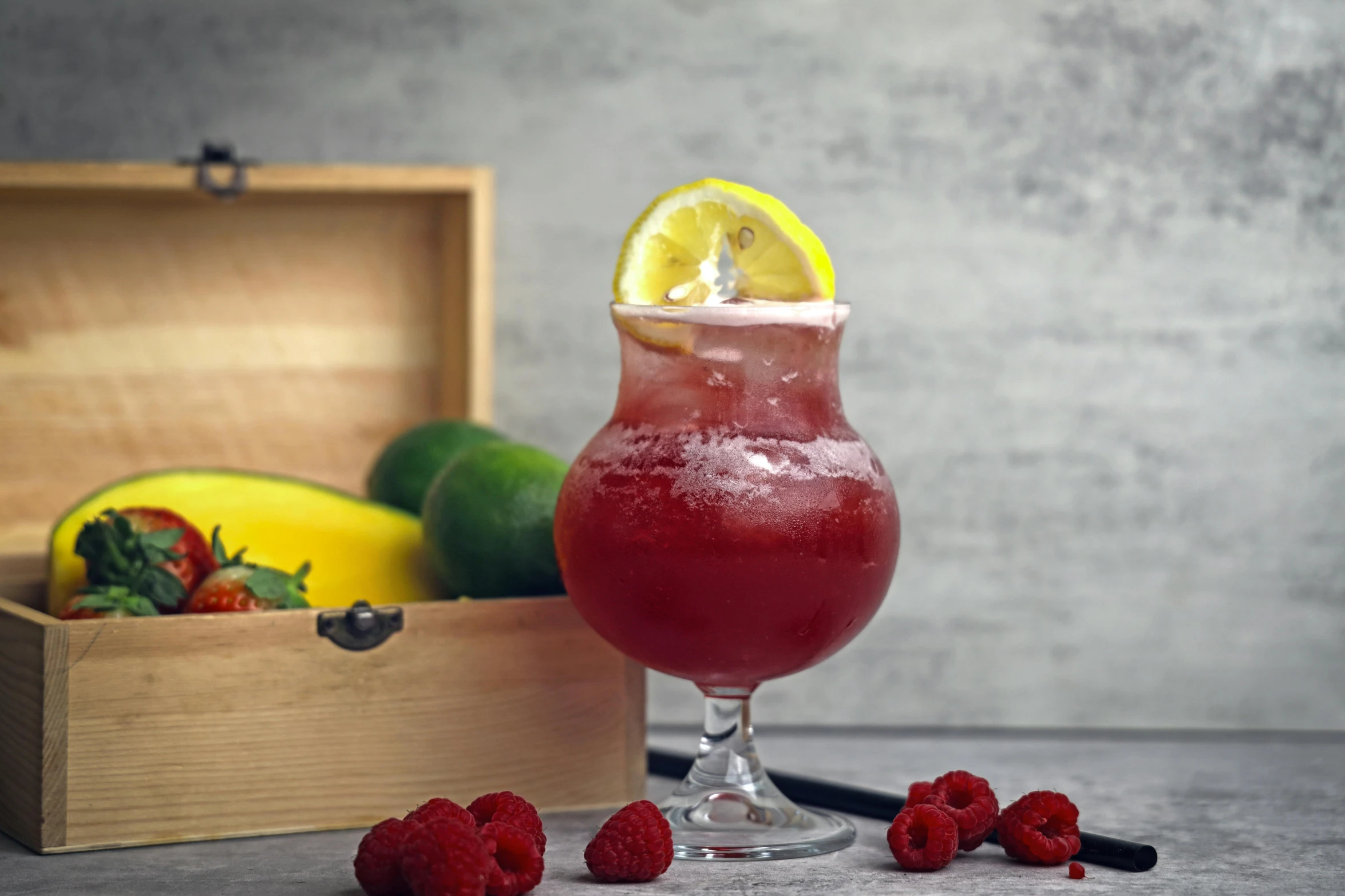 a red cocktail with a lemon wedge on the rim