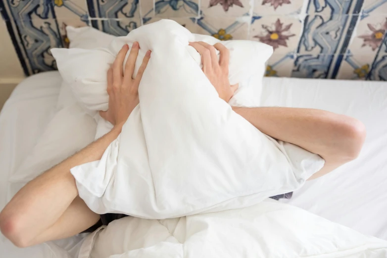 a man laying on top of a white bed covered in pillows