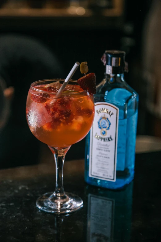 a glass filled with fruity alcohol sitting next to a bottle of alcohol