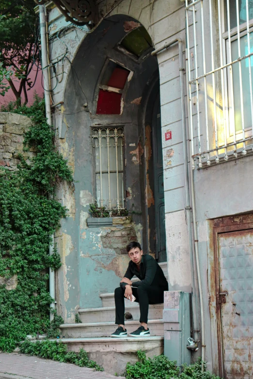 the man sits on a step of an abandoned house