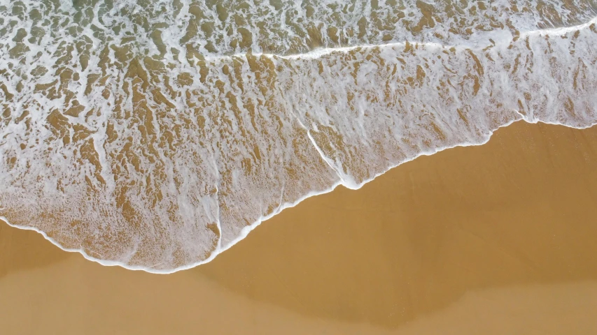 the view of waves from above on a sandy beach