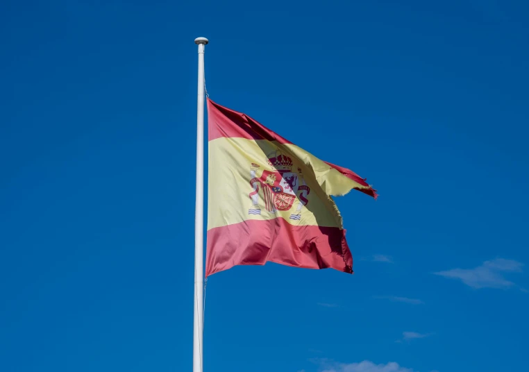 the spanish flag waving in the wind with blue sky in the background