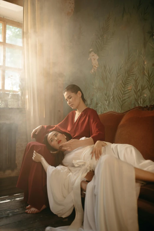 woman holding another woman in a red dress sitting on a brown couch