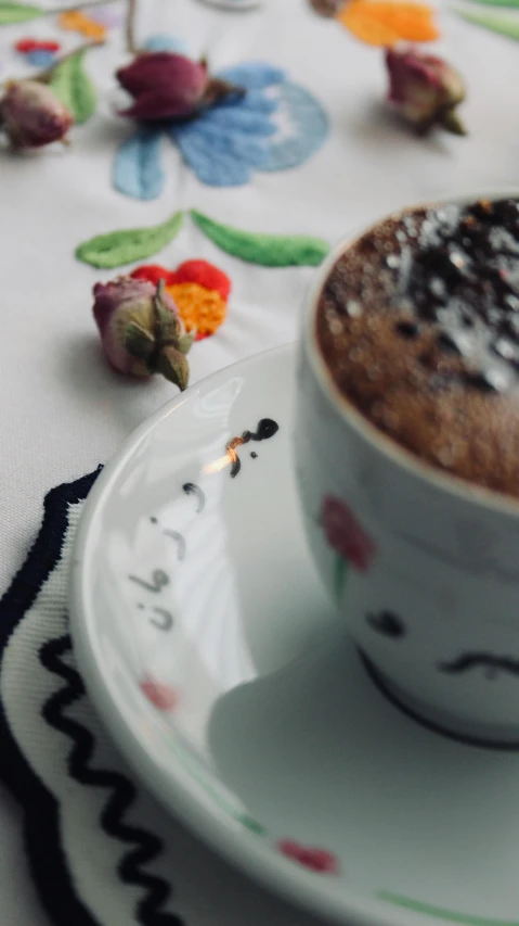 a plate with a cup on it has a small piece of food in the middle of it