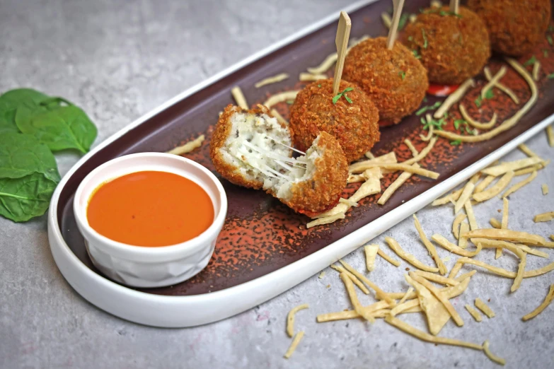 a appetizer platter with food, sauce and spinach leaves on the side