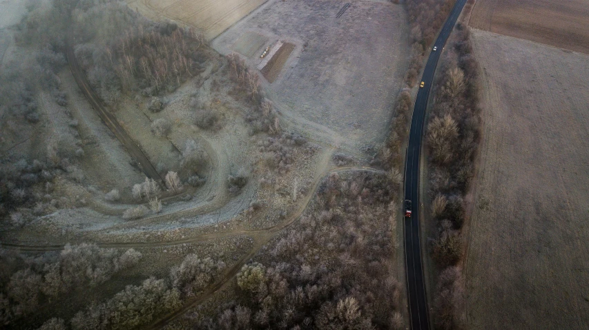 an aerial view of a road and tree covered field