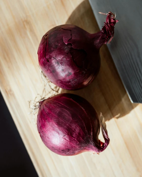 two large purple onions sitting on a wooden  board