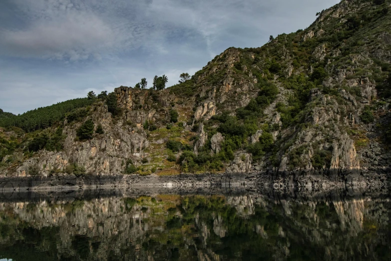 a mountain with trees on it is reflected in a river