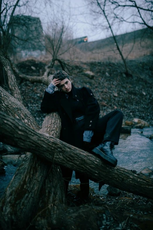 a person sitting on top of a log next to a river