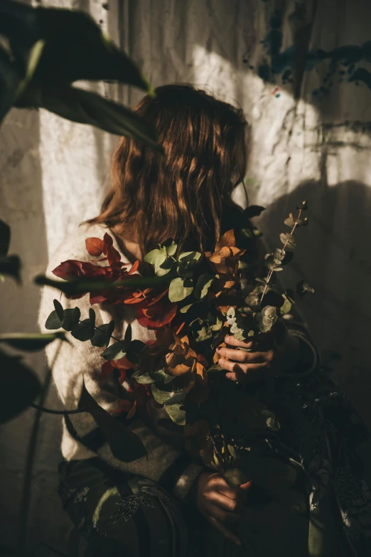 a woman holding some plants in her arms