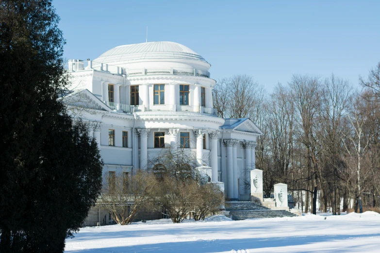 a big white building in the winter surrounded by trees