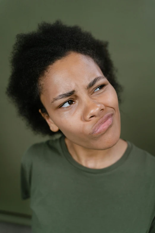 a girl in a green shirt with black hair looking at the camera