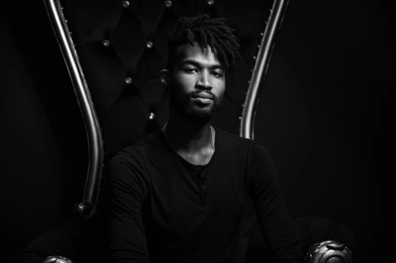 a man with dreadlocks sitting in front of a black background