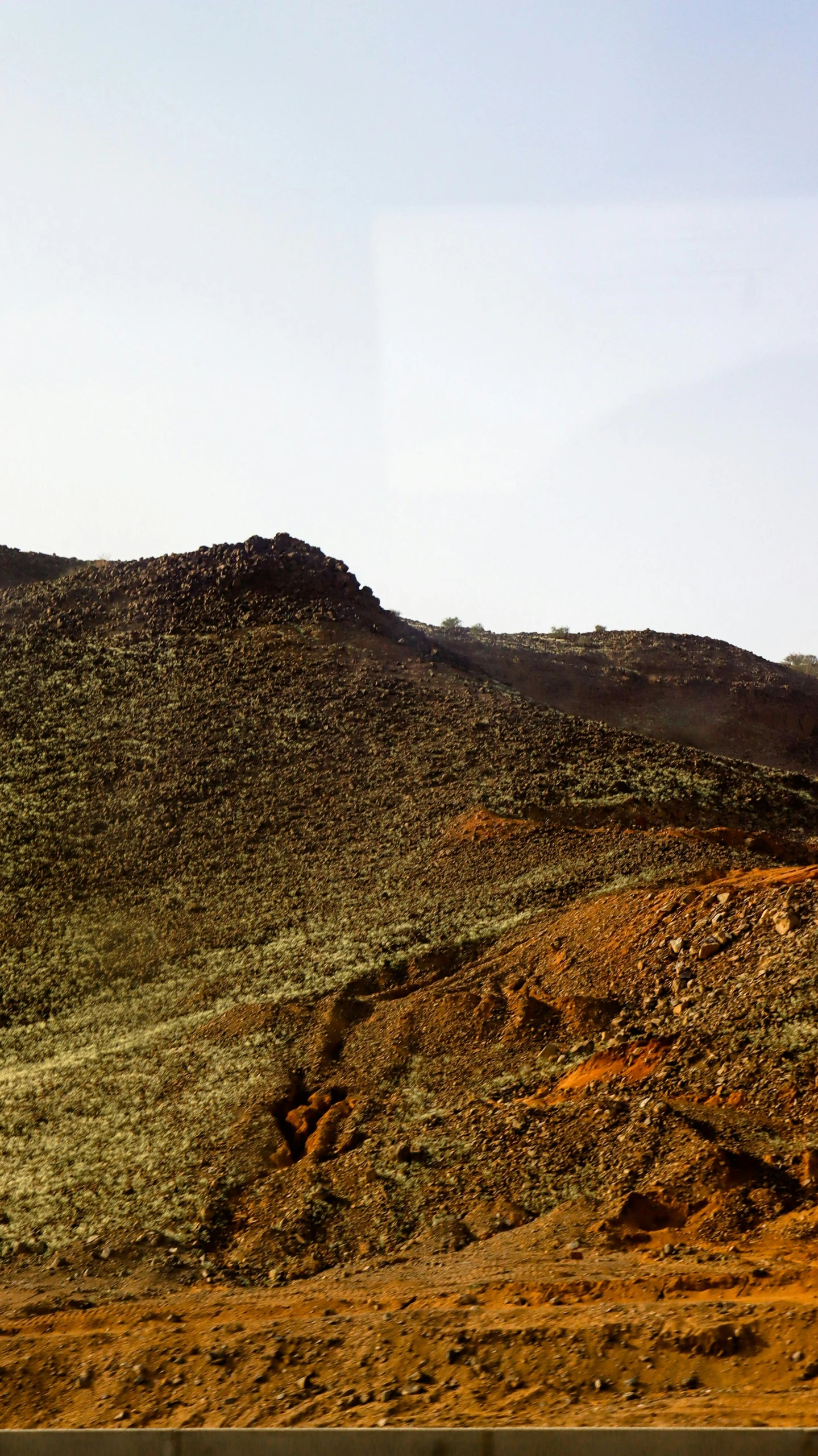 a lone sheep standing on the side of a hill