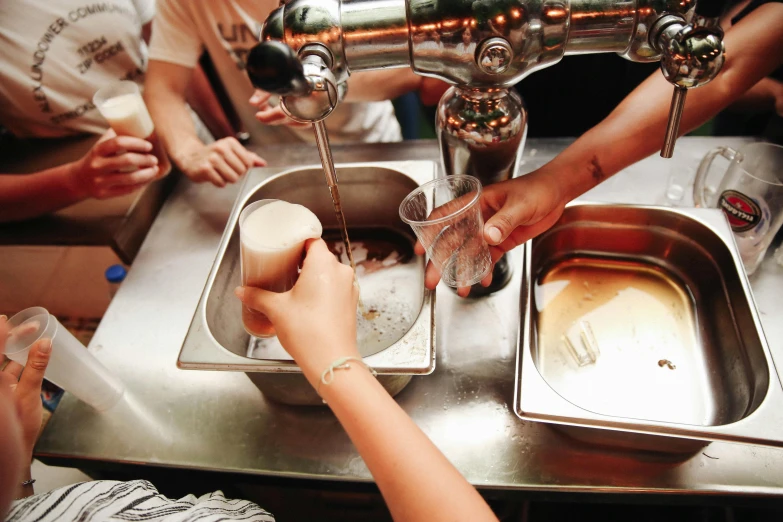 several people are reaching for food at a sink