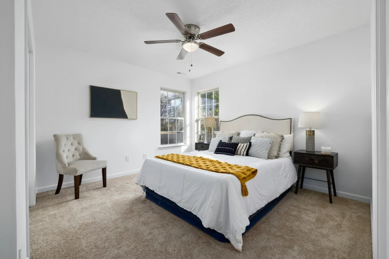 a large bedroom with a ceiling fan, bed and chair