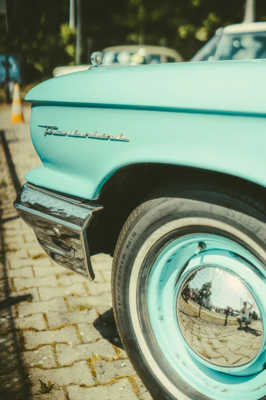 the reflection of people in the chrome wheels of a classic car