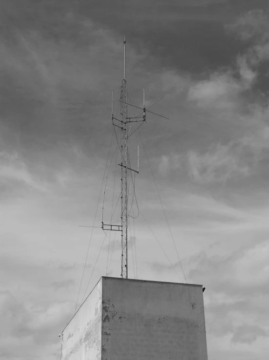 a tall antenna on top of a building under a cloudy sky