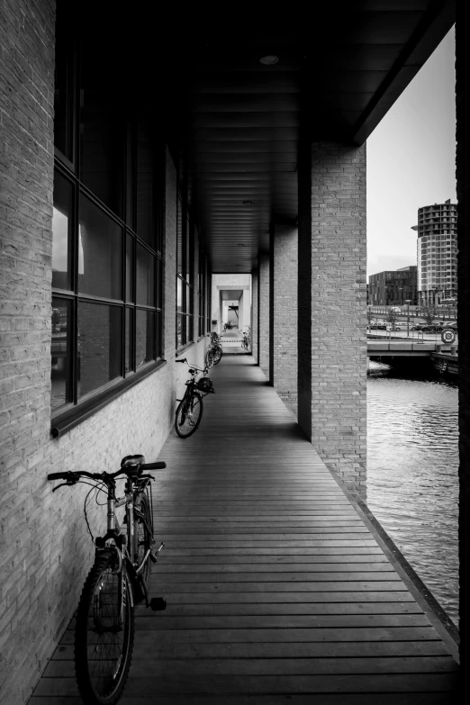 black and white pograph of bicycles parked along the side of a building