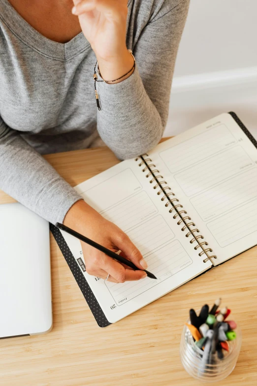 a woman sitting at a desk with a notebook and pen