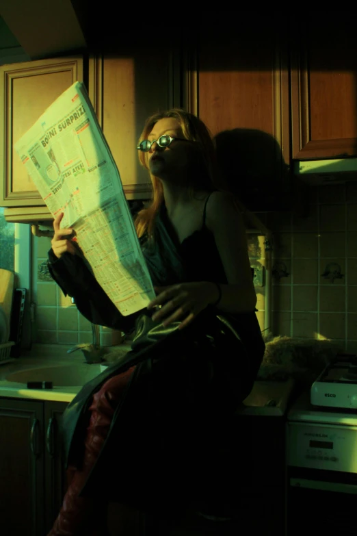 a woman sitting in the kitchen while reading a map