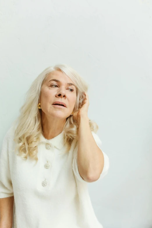 a woman with long white hair holding her hand to her ear