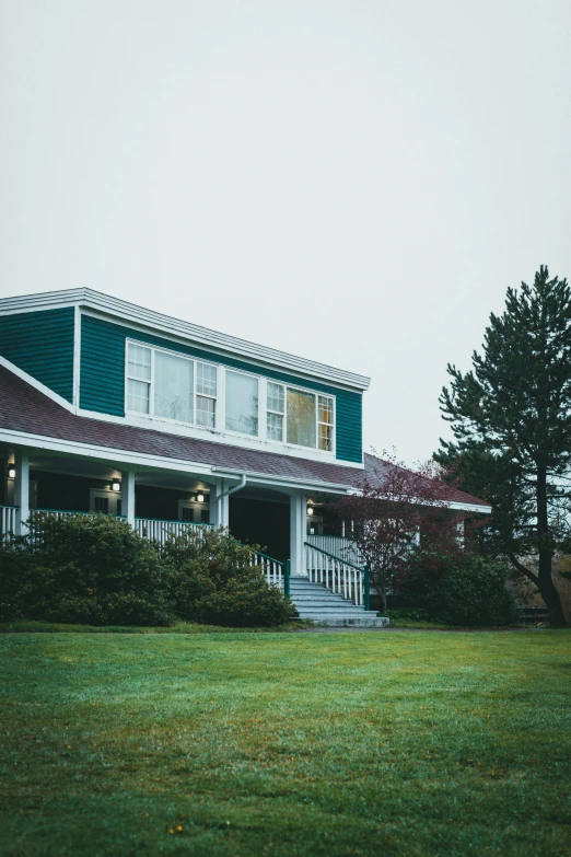 a large blue house sitting in a lush green field