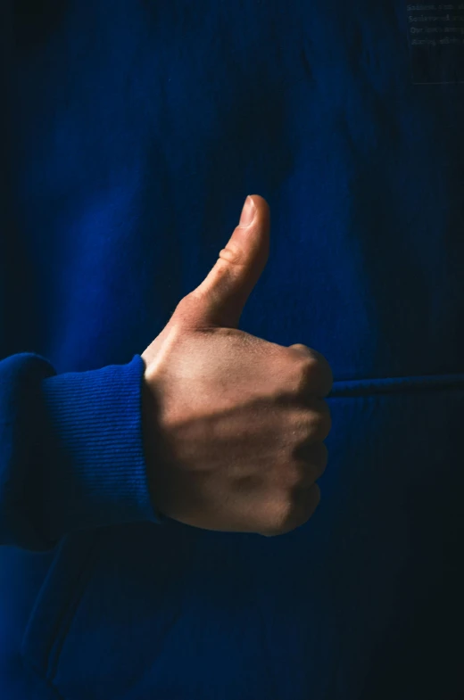 the person is gesturing their fingers while he is wearing blue clothing