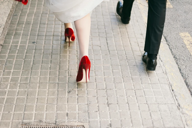 two people wearing red stilfetti shoes walking down the street