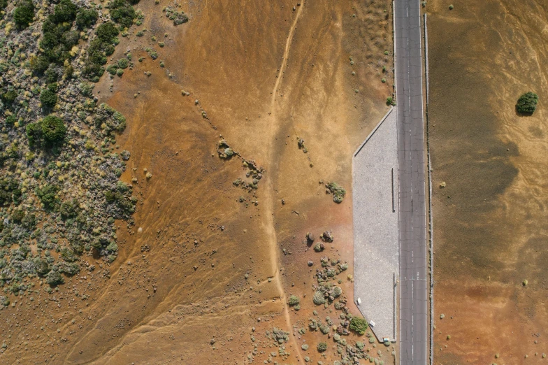 an airplane flying over the top of a dirt and grass hill