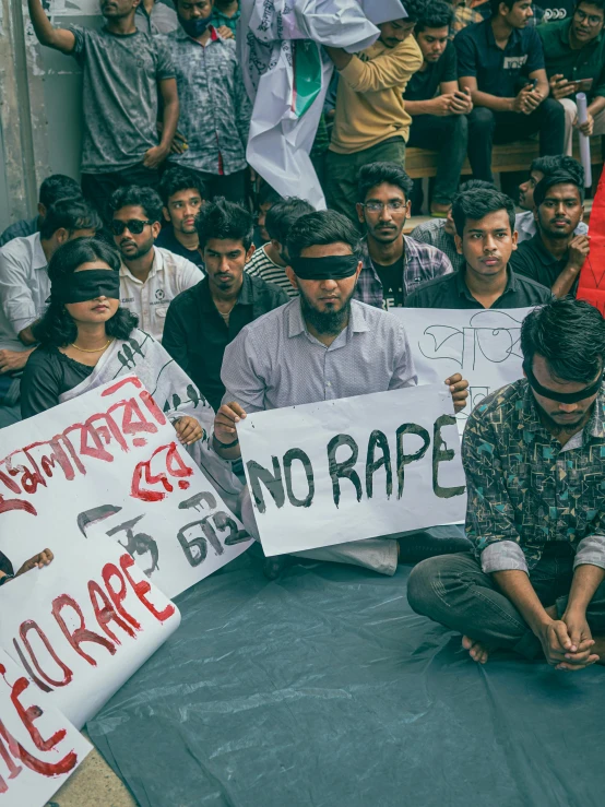 a group of people sitting on the ground holding protest signs