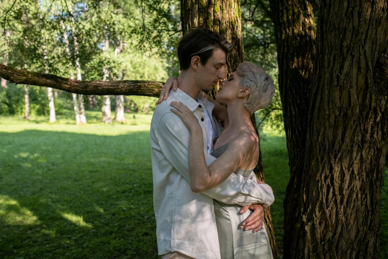 a couple kissing in the woods near a tree