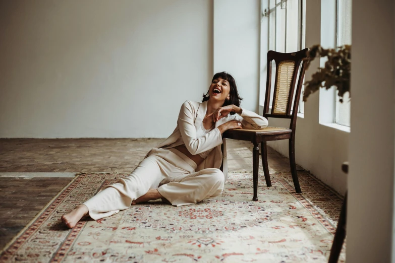 a young woman sits on the floor and laughs