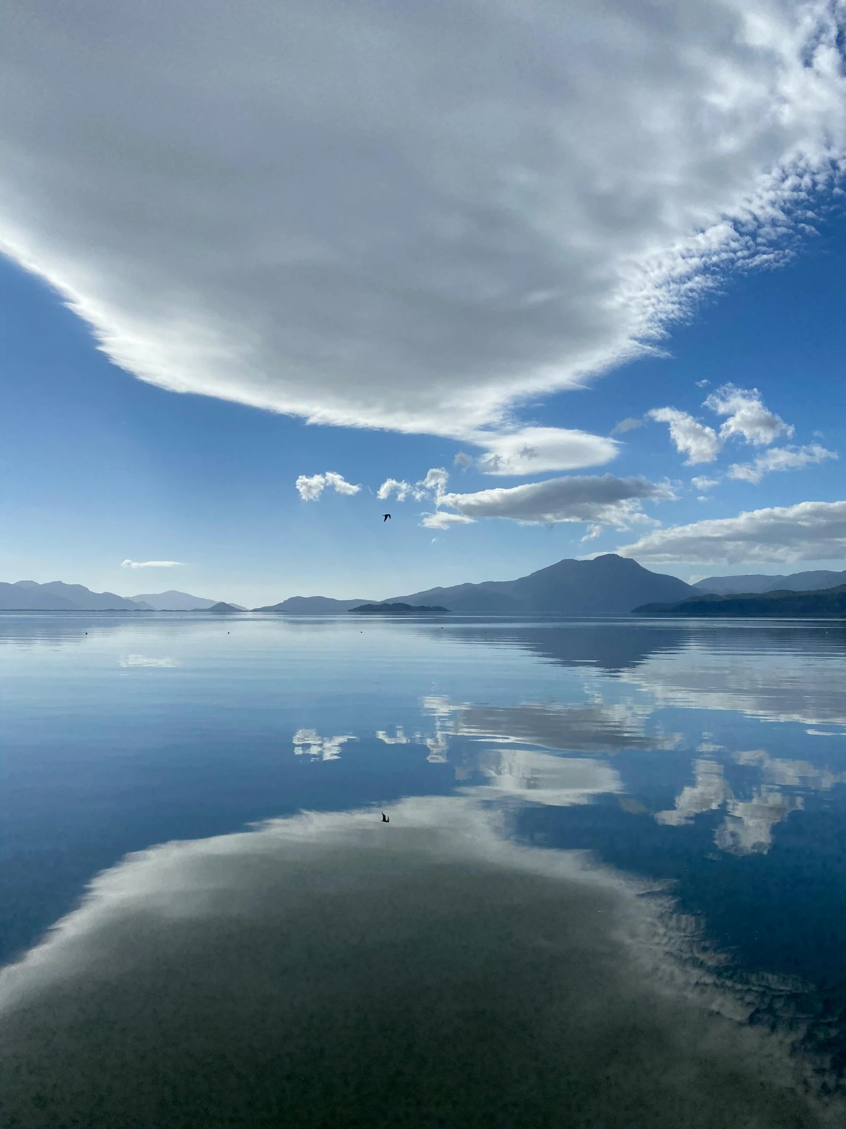 a cloud filled blue sky hangs over a calm bay