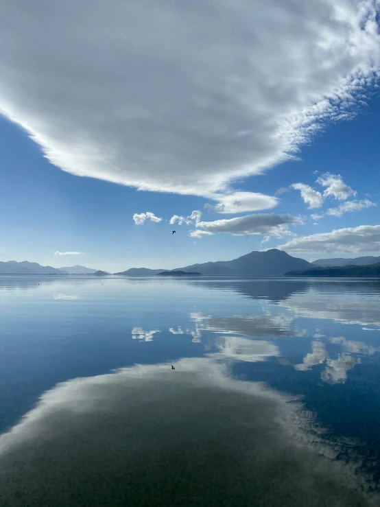 a cloud filled blue sky hangs over a calm bay