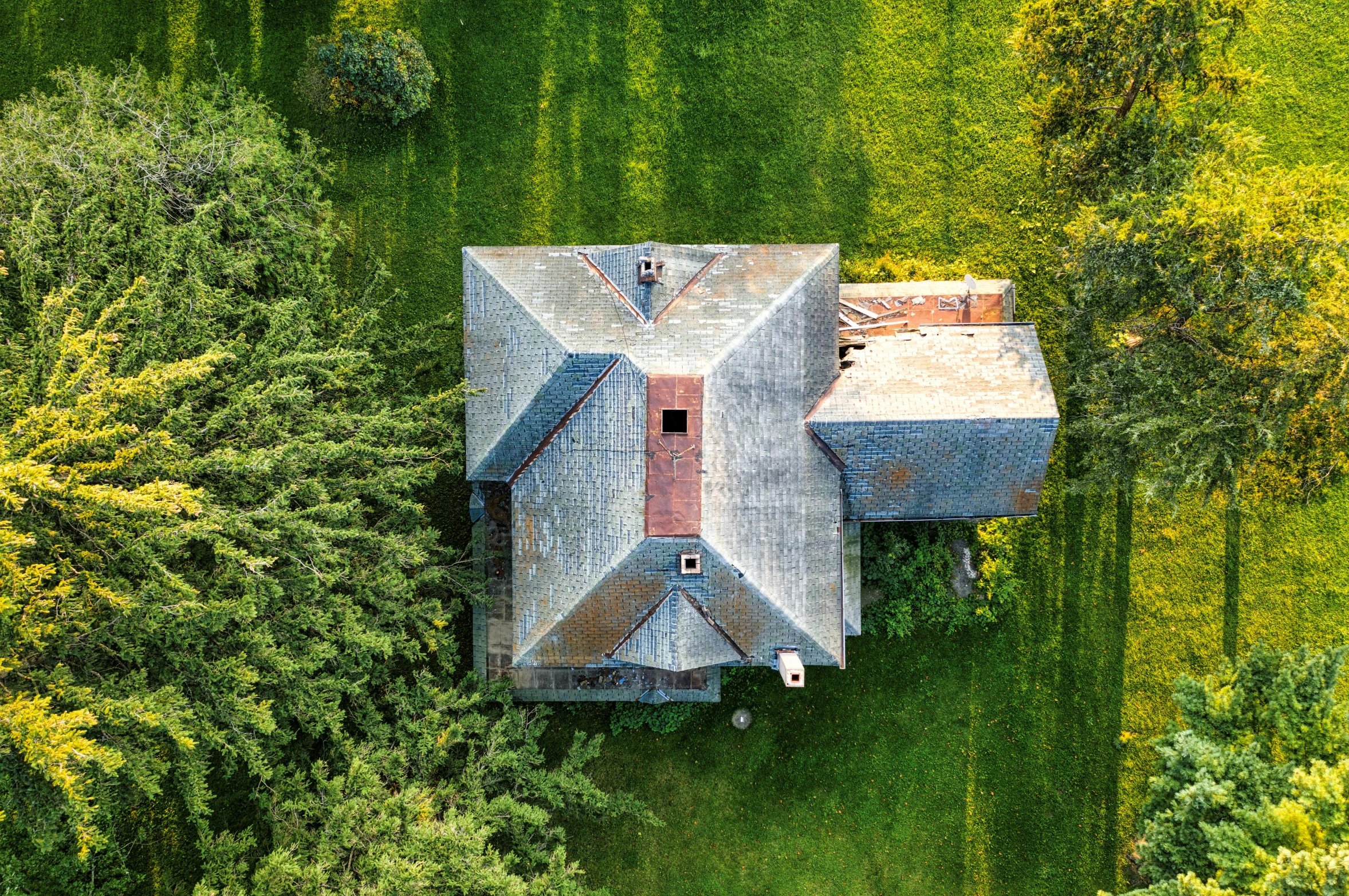 an aerial view of a house in the middle of a green field