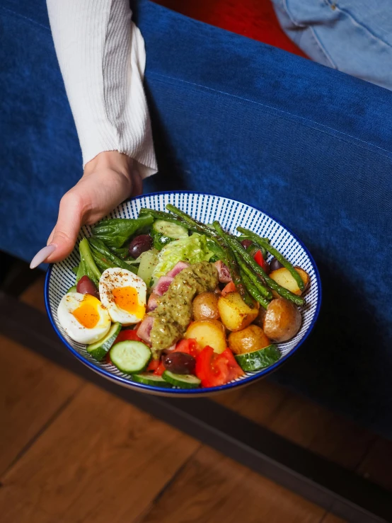 a close up of a person's hands holding a bowl of fruit and veggies