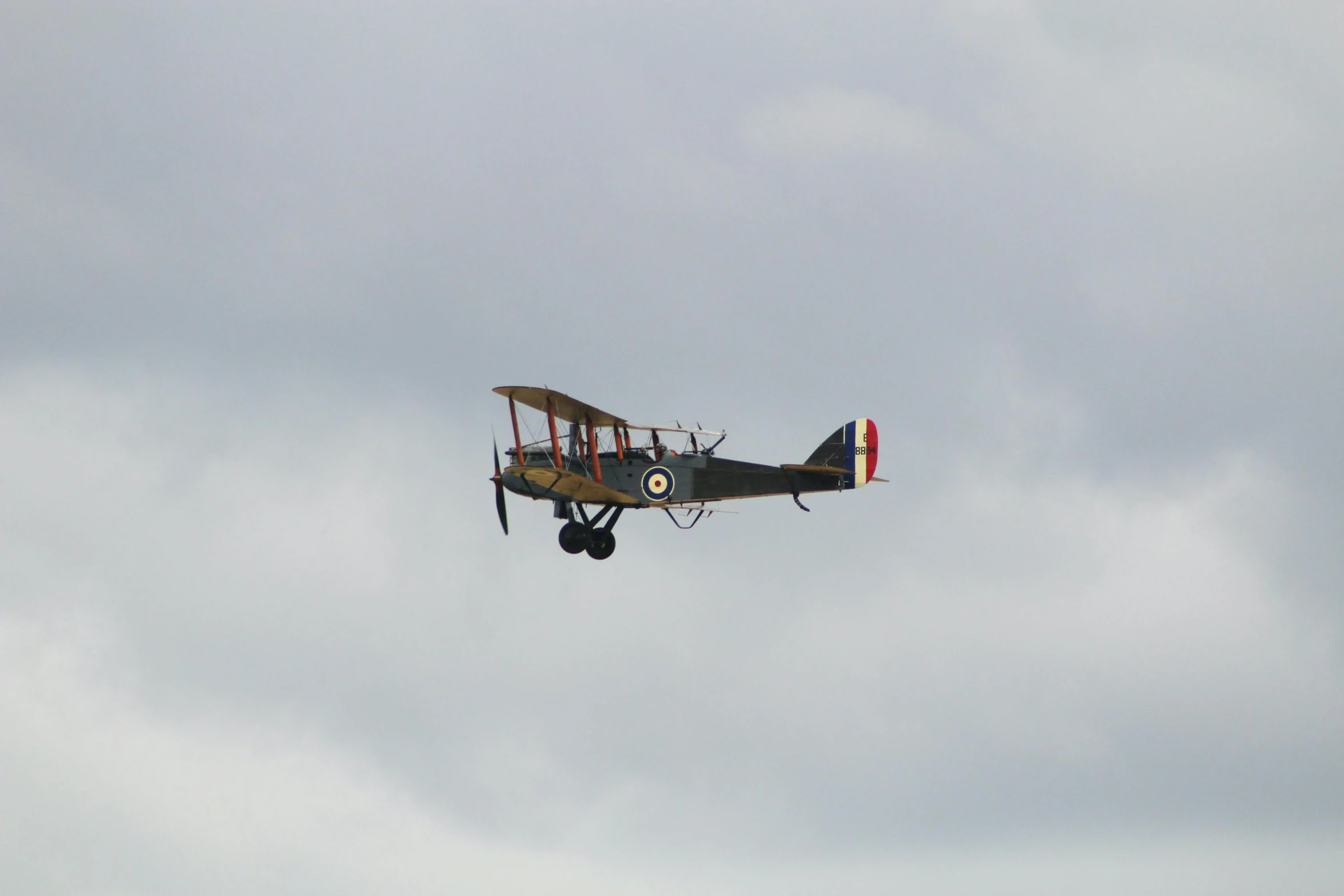 an old plane flying in the cloudy sky