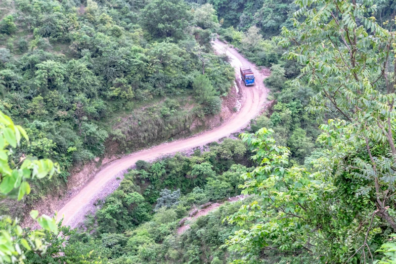 a truck on the road that is winding in a mountain