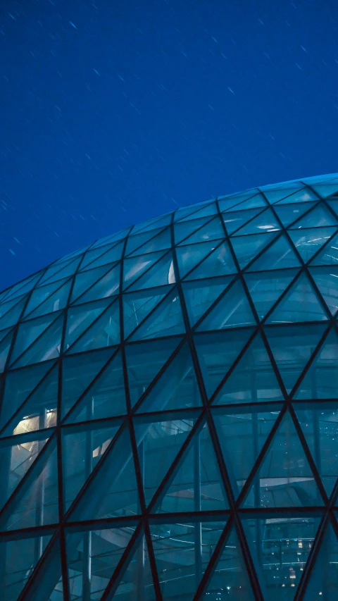 a large pyramid shaped glass building lit up at night